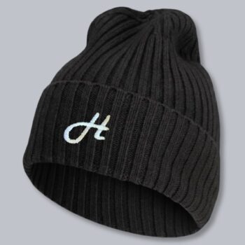 Merino-Mütze Mary in Schwarz mit gesticktem Logo auf dem Umschlag – Werbeartikel von Huthelden